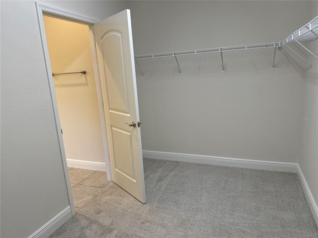A walk-in closet features gray carpeting, white walls, wire shelving, and an open doorway — 1409 MARJORIE LANE, NORTH PORT, FL