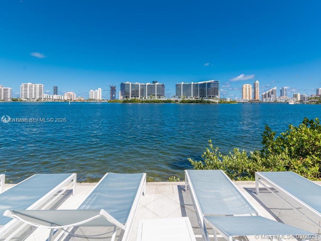 A view of the water and city skyline from a patio with lounge chairs — AVENTURA, FL