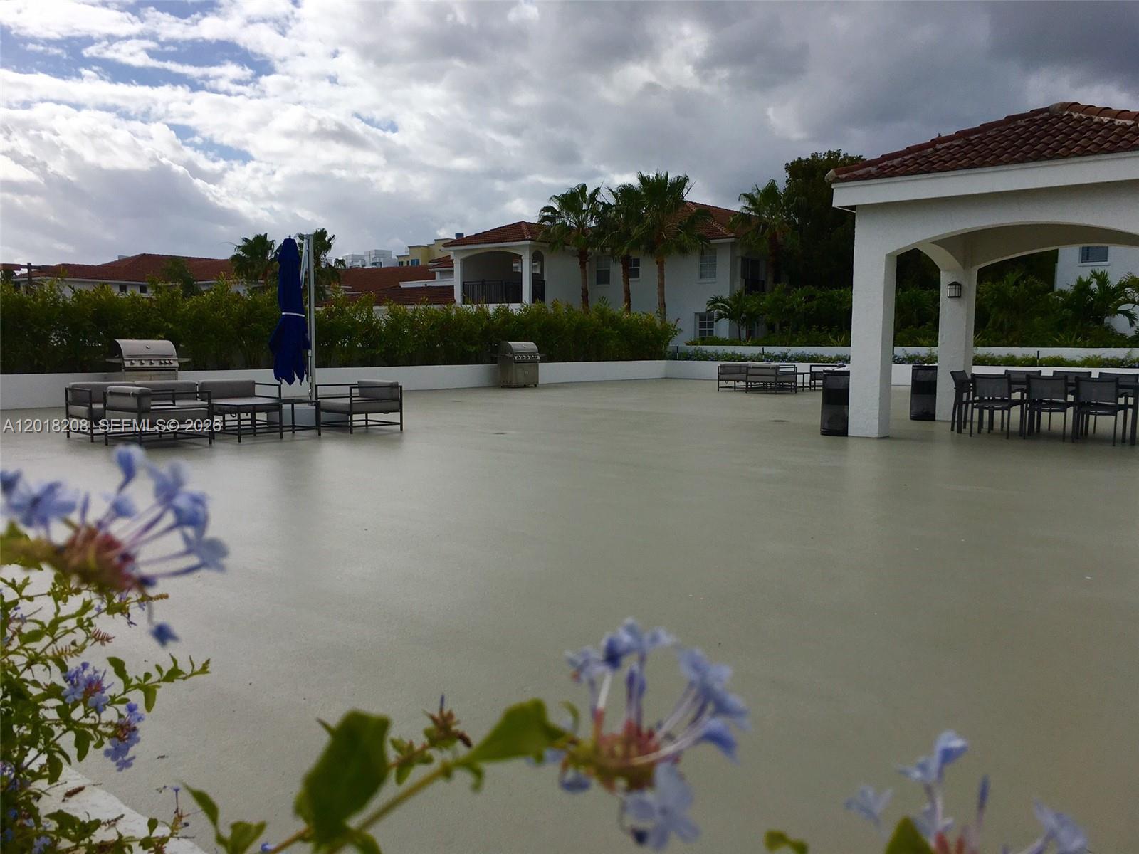 An outdoor patio area features lounge seating, dining tables, grills, and a covered pavilion — AVENTURA, FL