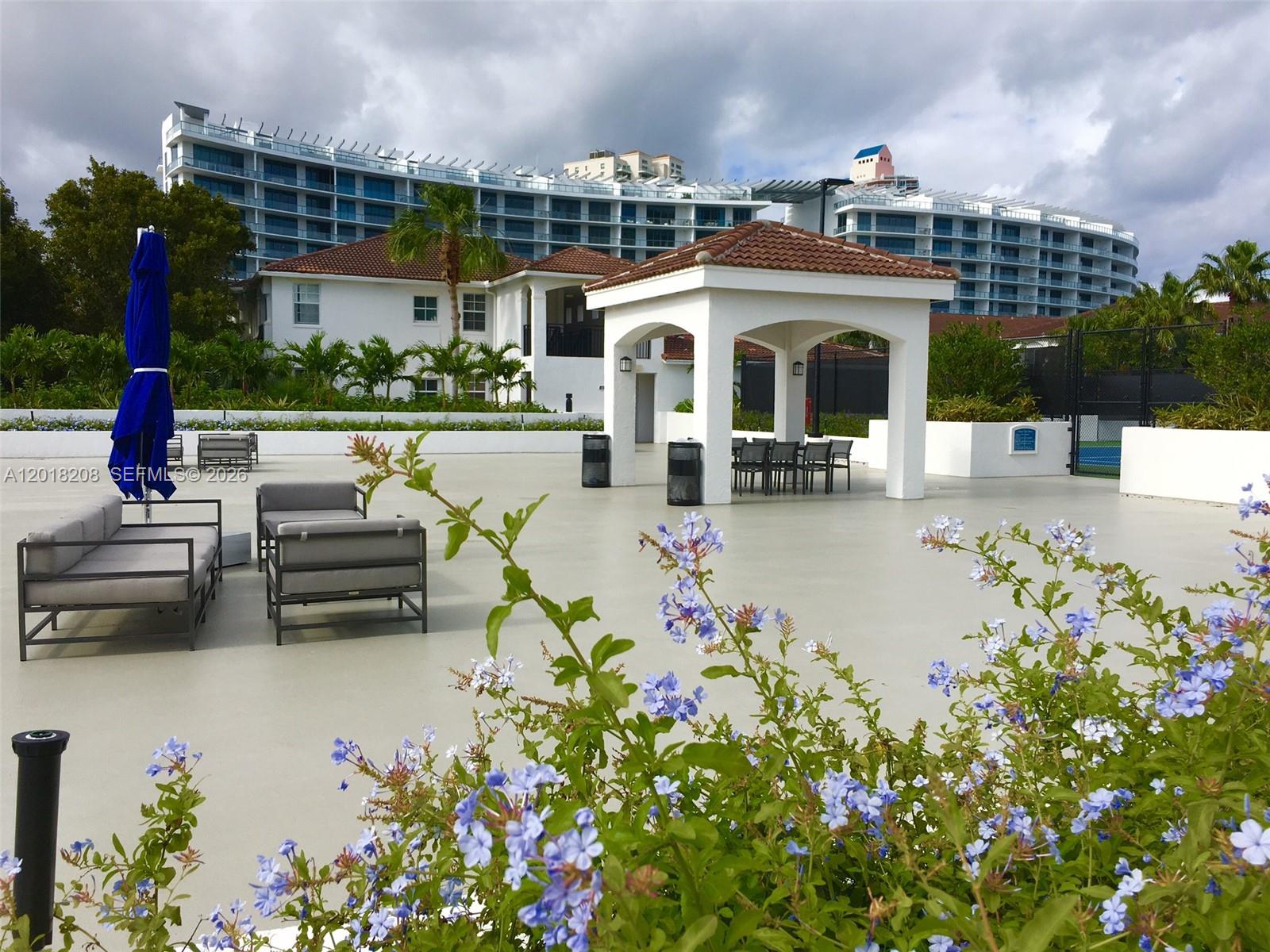 An outdoor patio features a white gazebo, lounge seating, and a blue umbrella — AVENTURA, FL