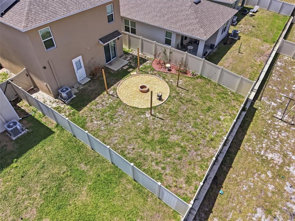 An aerial view of a fenced backyard featuring a circular gravel fire pit area — 1356 BERRY LANE, DAVENPORT, FL
