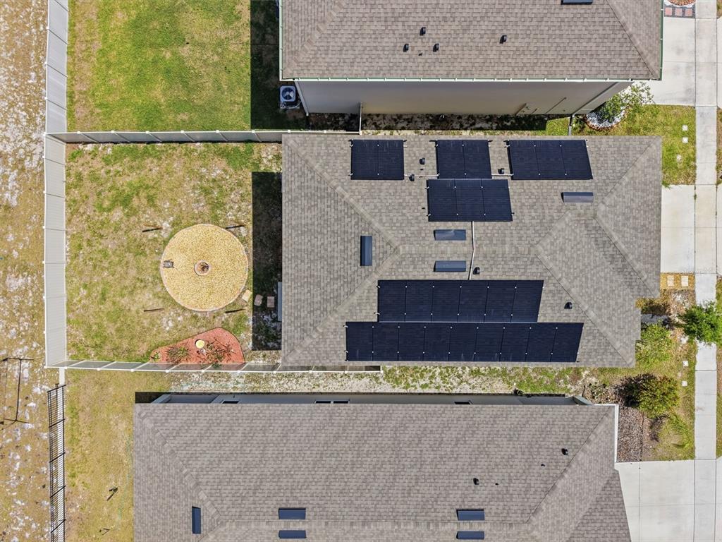 An aerial view shows a house with solar panels on its roof and a backyard — 1356 BERRY LANE, DAVENPORT, FL