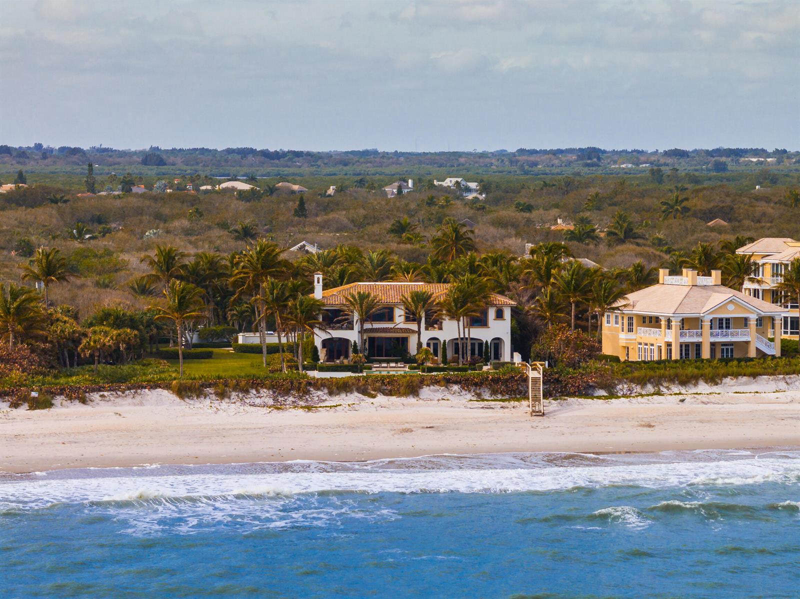 An aerial view of two large beachfront houses surrounded by palm trees and coastal vegetation — 10 Ocean Lane, Vero Beach FL 32963, VERO BEACH, FL