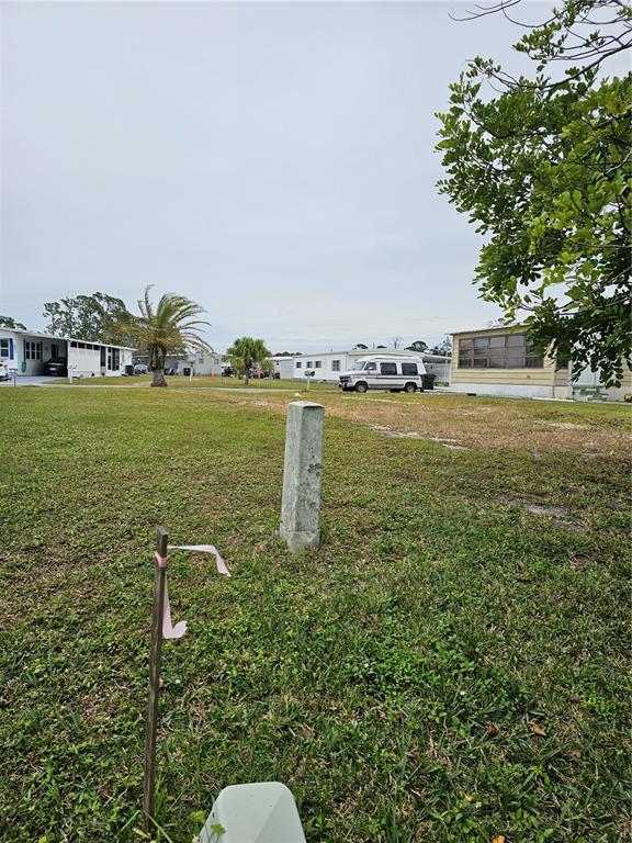 A vacant grassy lot features a survey marker and a wooden stake with pink tape — 6811 HOLO COURT, NORTH PORT, FL