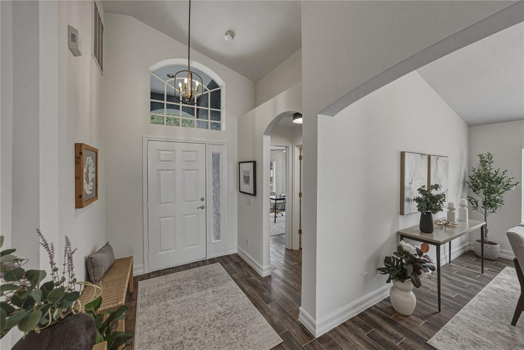 A bright entryway features a white front door, arched transom window, and dark wood-look flooring — 4224 BRANCHSIDE LANE, WESLEY CHAPEL, FL