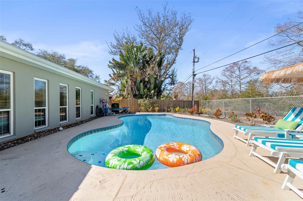 A swimming pool with two inflatable rings sits on a patio beside a house — 13347 88TH PLACE, SEMINOLE, FL
