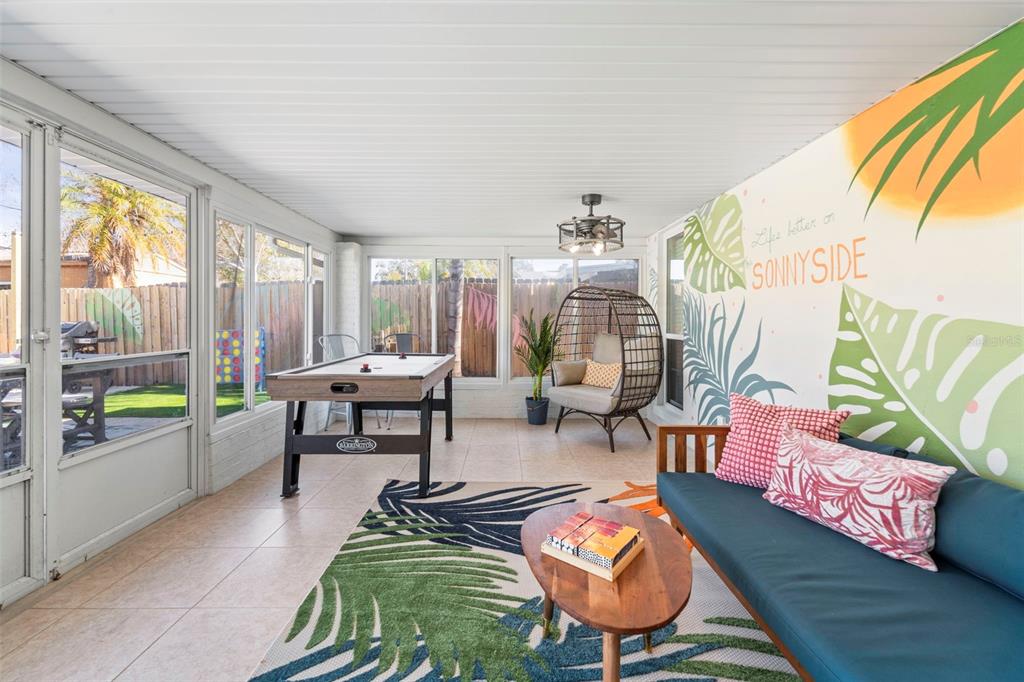 A sunroom features a mural, air hockey table, hanging chair, and a blue sofa — 13347 88TH PLACE, SEMINOLE, FL