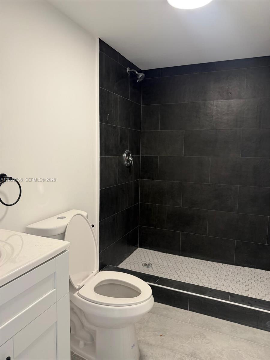 A bathroom features a walk-in shower with black tile walls and a white hexagonal floor — 147 Nw 59th St # 301, Miami FL 33127, MIAMI, FL