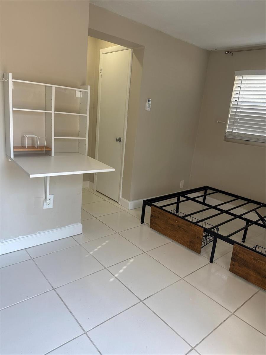 A bedroom with white tile floors, a wall-mounted desk, and a metal bed frame — 299 SE 12th Avenue, Deerfield Beach FL 33441, DEERFIELD BEACH, FL