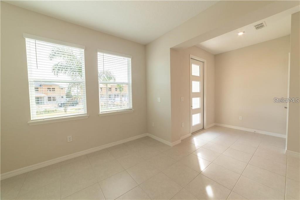 An empty room with light tile flooring, two windows, and a modern glass-paneled door — 16306 PRAIRIE SCHOOL DRIVE, WINTER GARDEN, FL