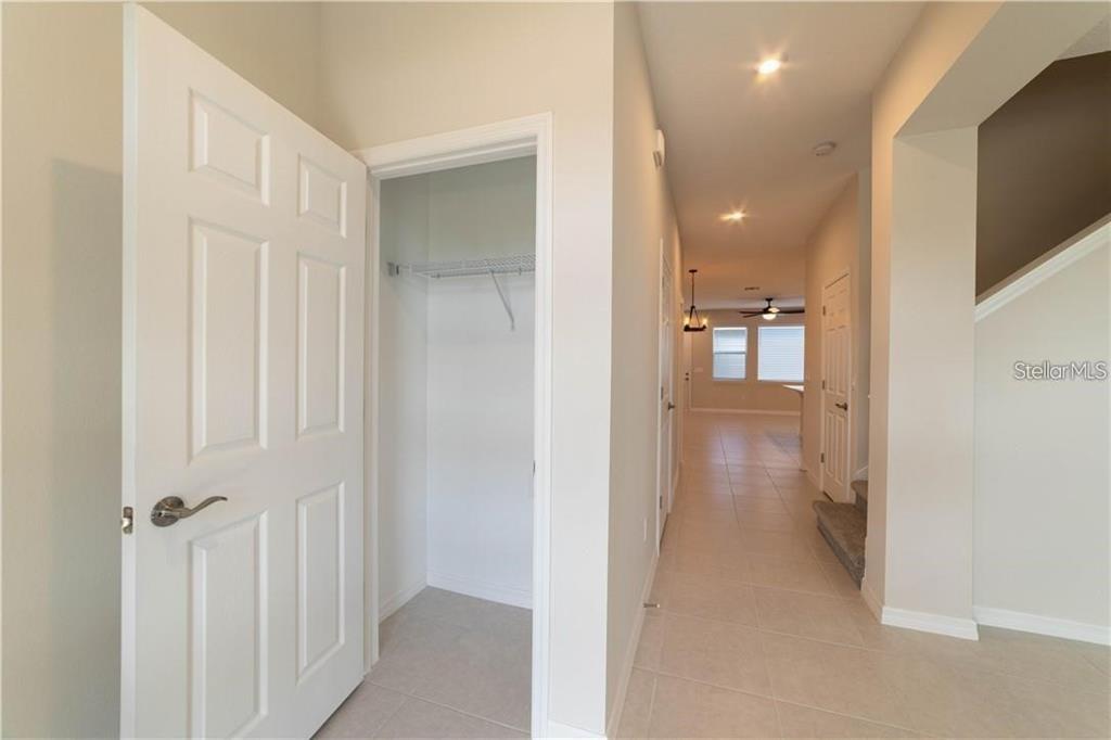 A hallway with tile flooring leads toward an open living area with a staircase nearby — 16306 PRAIRIE SCHOOL DRIVE, WINTER GARDEN, FL