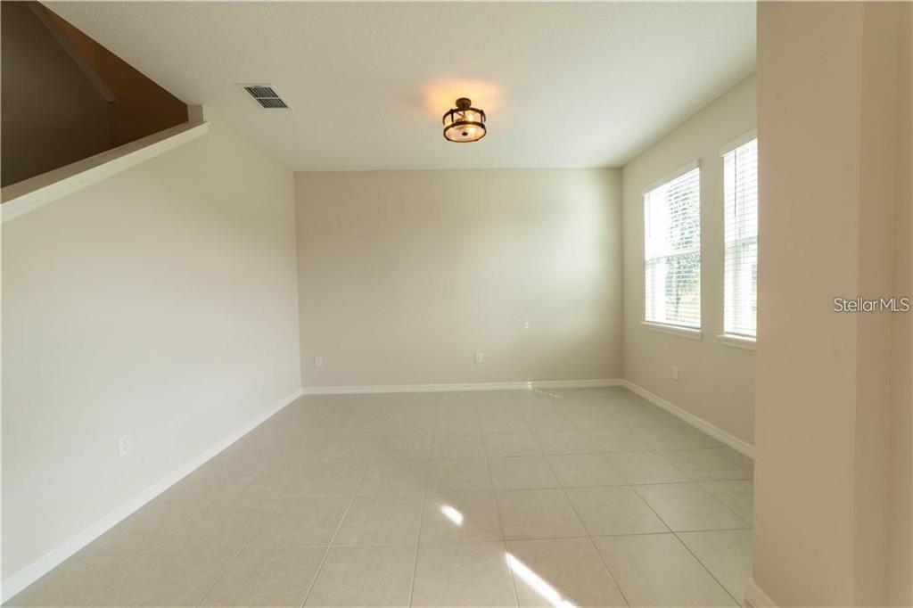 An empty room with beige walls, light tile flooring, and a central ceiling light fixture — 16306 PRAIRIE SCHOOL DRIVE, WINTER GARDEN, FL