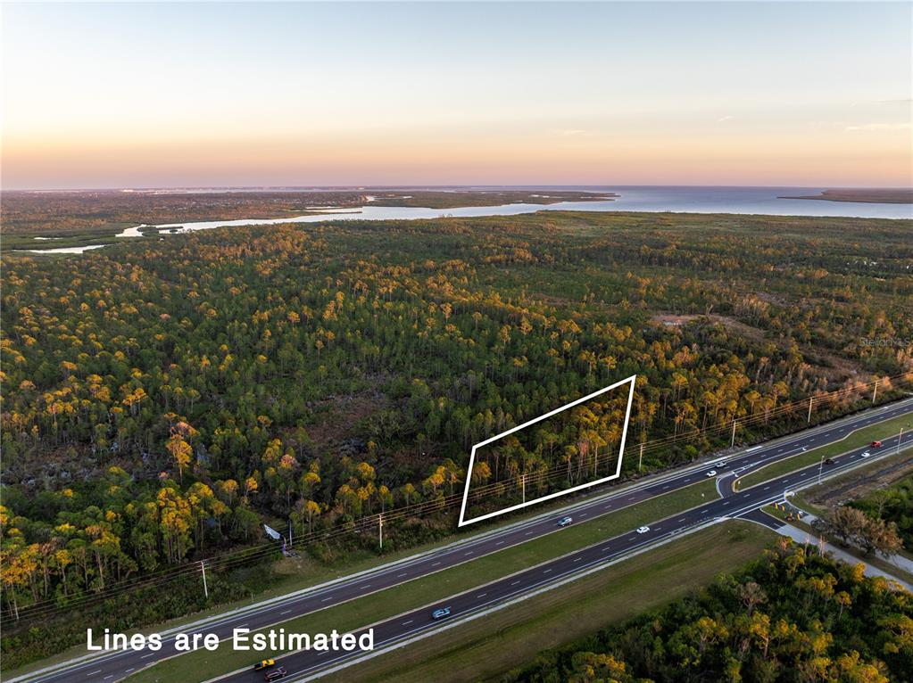 An aerial view shows a wooded lot outlined in white adjacent to a multi-lane highway — 3536 EL JOBEAN ROAD, PORT CHARLOTTE, FL