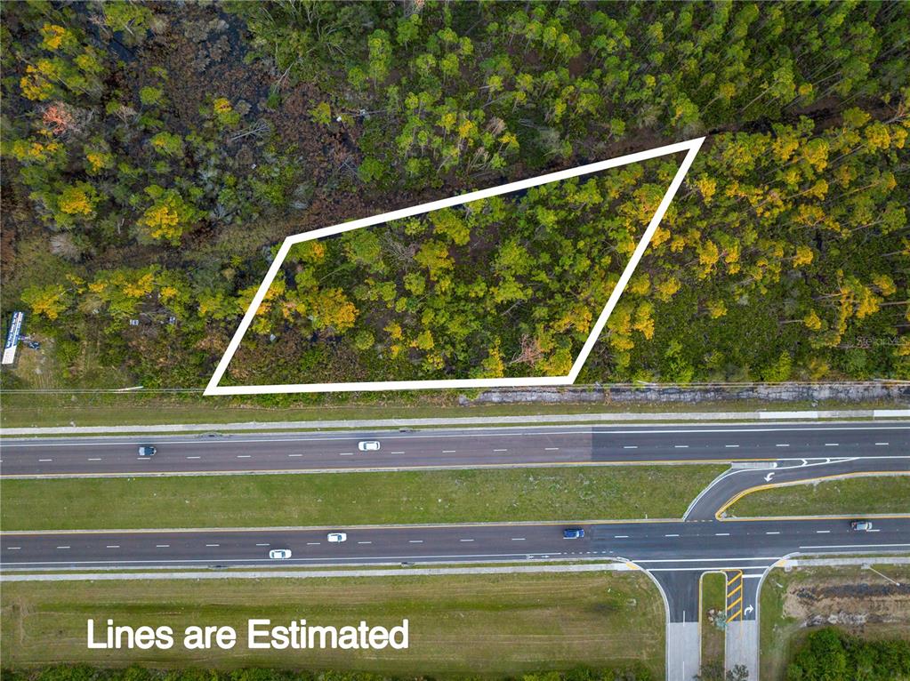 An aerial view shows a wooded plot of land outlined in white next to a highway — 3536 EL JOBEAN ROAD, PORT CHARLOTTE, FL