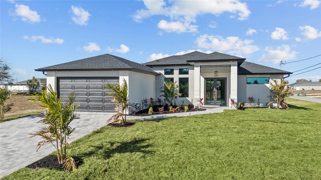 A modern single-story house with a gray garage, white stucco exterior, and a paved driveway — 1030 NE 2ND AVENUE, CAPE CORAL, FL