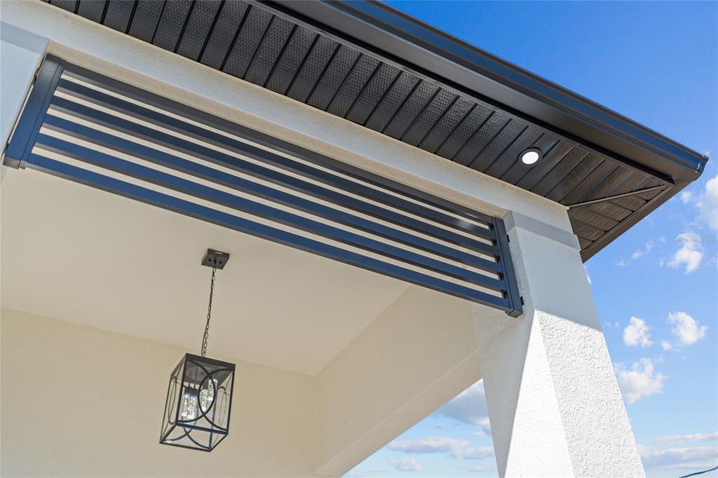 A low-angle view of a covered patio featuring a slatted privacy screen and hanging lantern — 1030 NE 2ND AVENUE, CAPE CORAL, FL