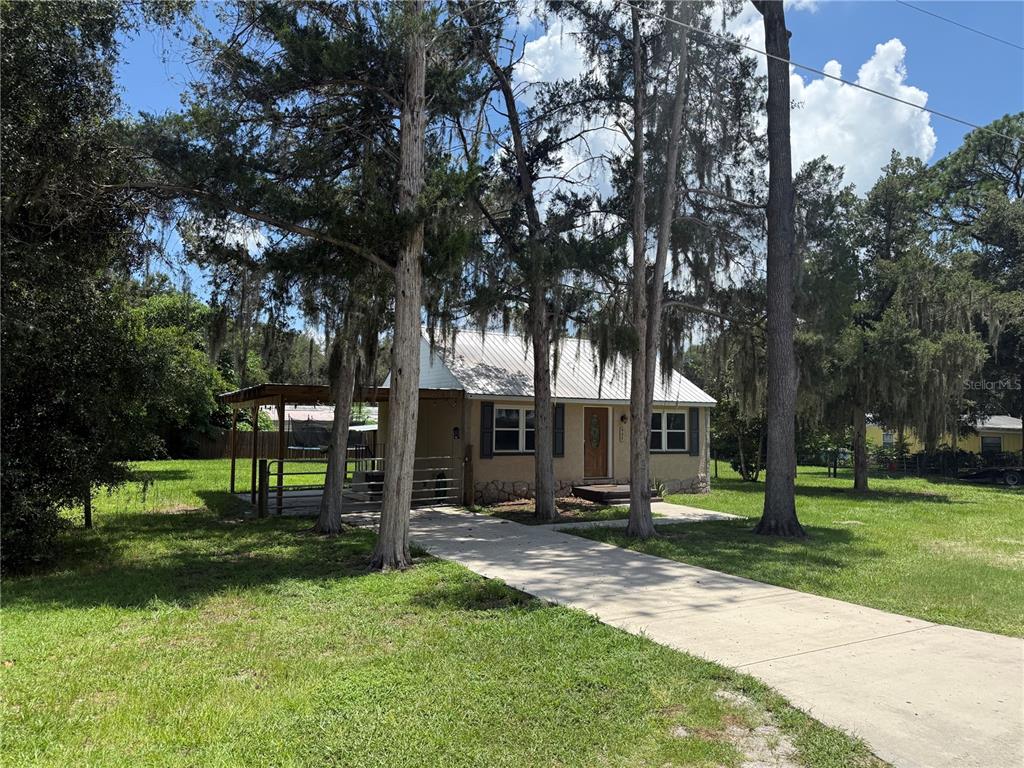 A single-story house with a metal roof, a carport, and a concrete driveway — 937 COUNTY ROAD 481W, LAKE PANASOFFKEE, FL