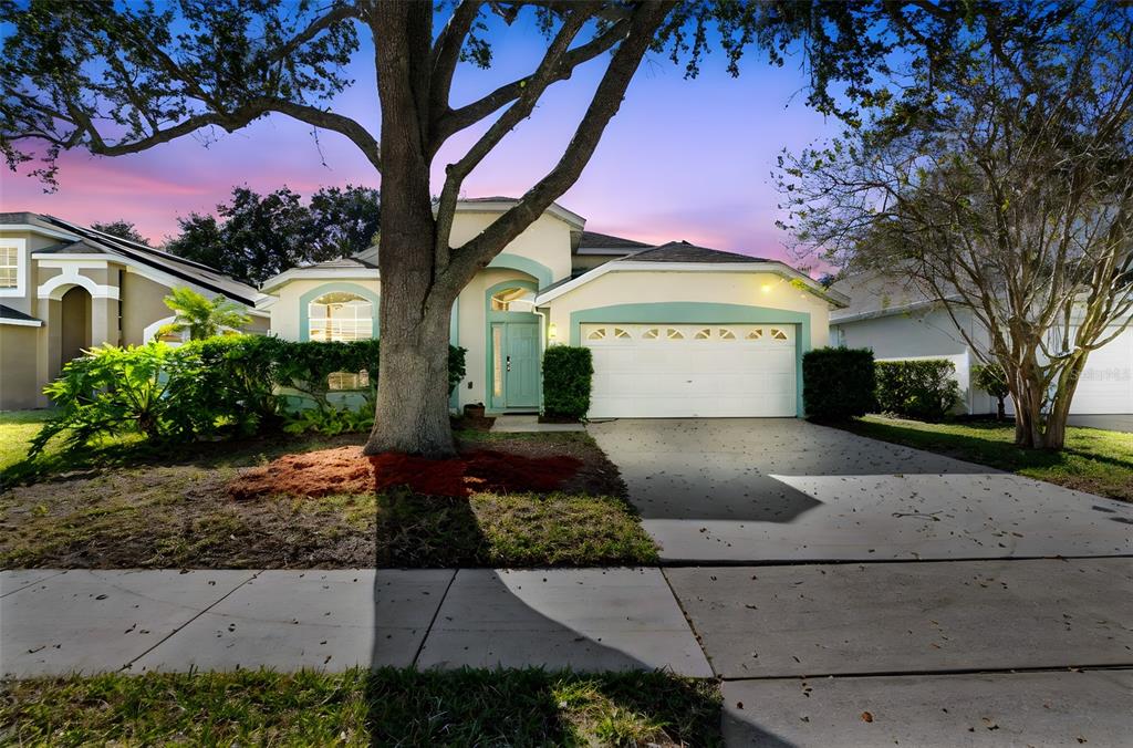 A single-story house with a white garage, teal trim, and a large tree in front — 2640 HERON LANDING COURT, ORLANDO, FL