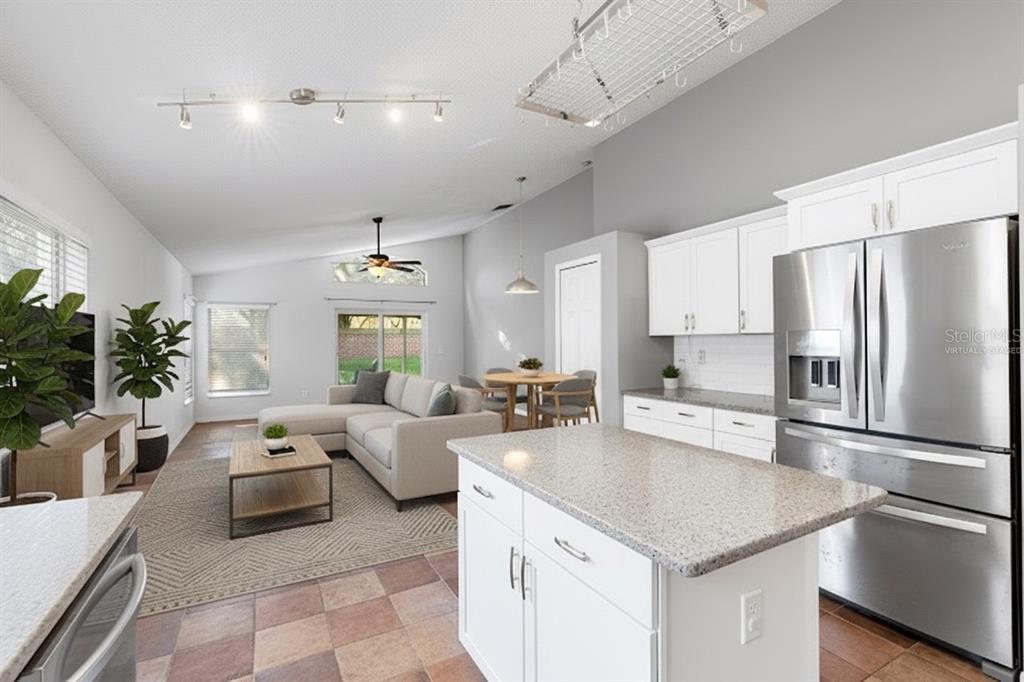 An open-concept kitchen and living area with white cabinets, granite countertops, and tile flooring — 2640 HERON LANDING COURT, ORLANDO, FL