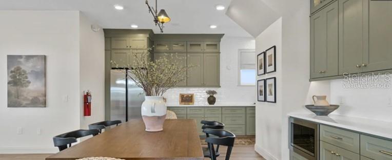 A kitchen with sage green cabinets, a wooden dining table, and black chairs — 3619 ROLLING RIDGE BEND, DAVENPORT, FL
