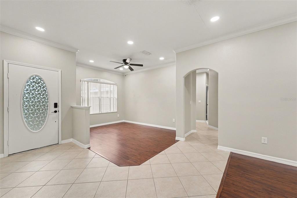An interior view shows a living area with tile flooring, wood-look laminate, and an arched entryway — 2056 CLAPPER TRAIL, APOPKA, FL