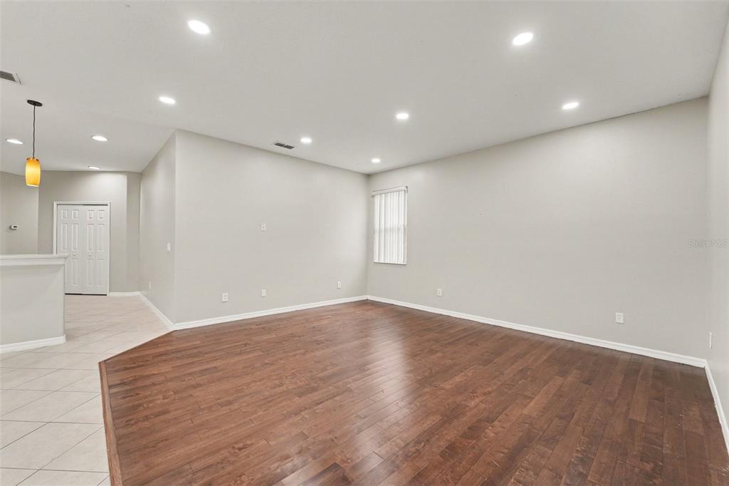 An empty living room with dark wood flooring, light gray walls, and recessed ceiling lights — 2056 CLAPPER TRAIL, APOPKA, FL