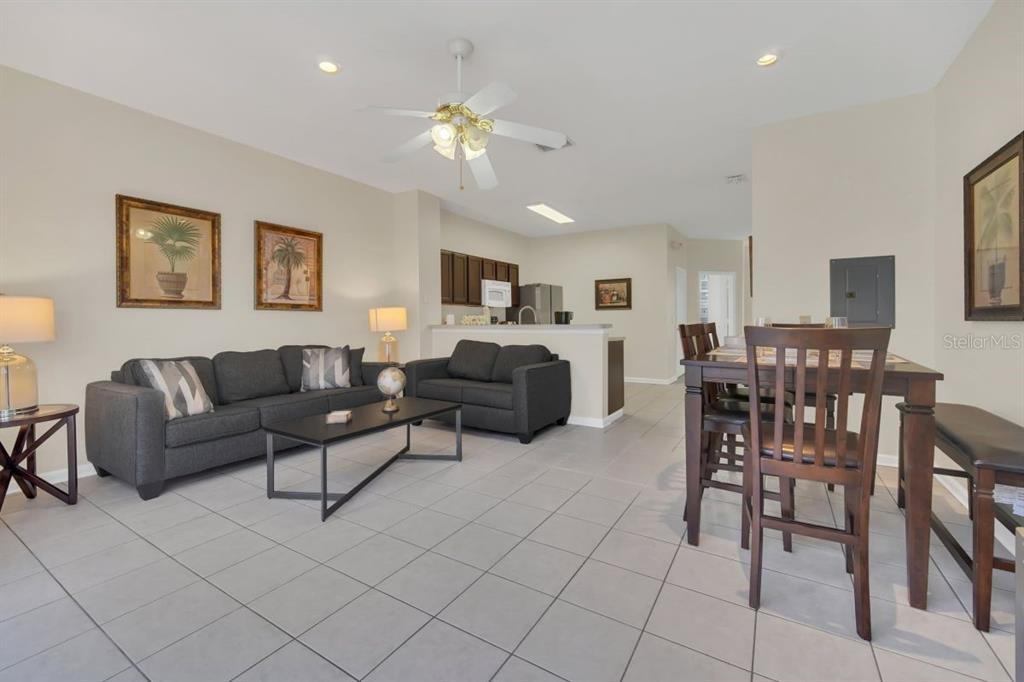 A living room and dining area with tile floors, dark furniture, and an open kitchen — 2545 RENSHAW STREET, KISSIMMEE, FL