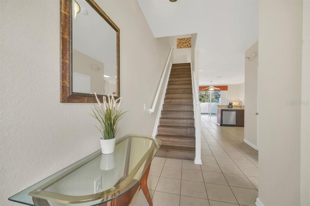 An entryway features a glass console table, a mirror, and stairs leading to an upper level — 2545 RENSHAW STREET, KISSIMMEE, FL