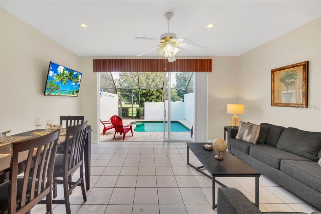 A living and dining area with tile floors opens to a patio with a pool — 2545 RENSHAW STREET, KISSIMMEE, FL