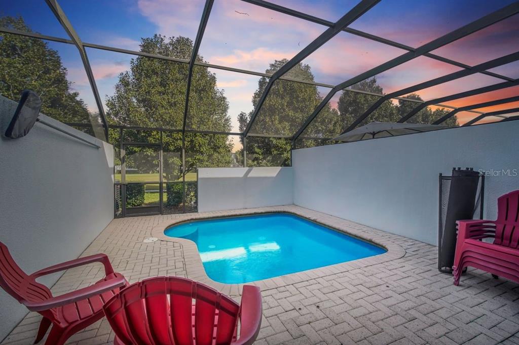 A small swimming pool sits on a brick patio inside a screened-in outdoor enclosure — 2545 RENSHAW STREET, KISSIMMEE, FL