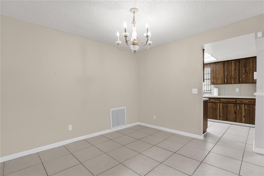 A dining area with a chandelier, beige walls, and light-colored tile flooring — 46 LANTANA DRIVE, DEBARY, FL