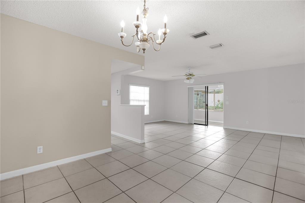 A dining area with a chandelier leads into a living room with tiled floors — 46 LANTANA DRIVE, DEBARY, FL