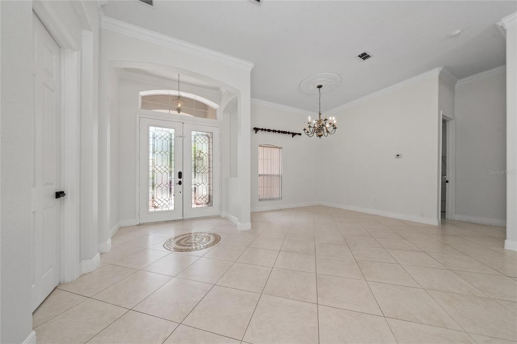An entryway features tile flooring, a decorative chandelier, and double glass-paneled front doors — 3540 VALLEYVIEW DR, KISSIMMEE, FL