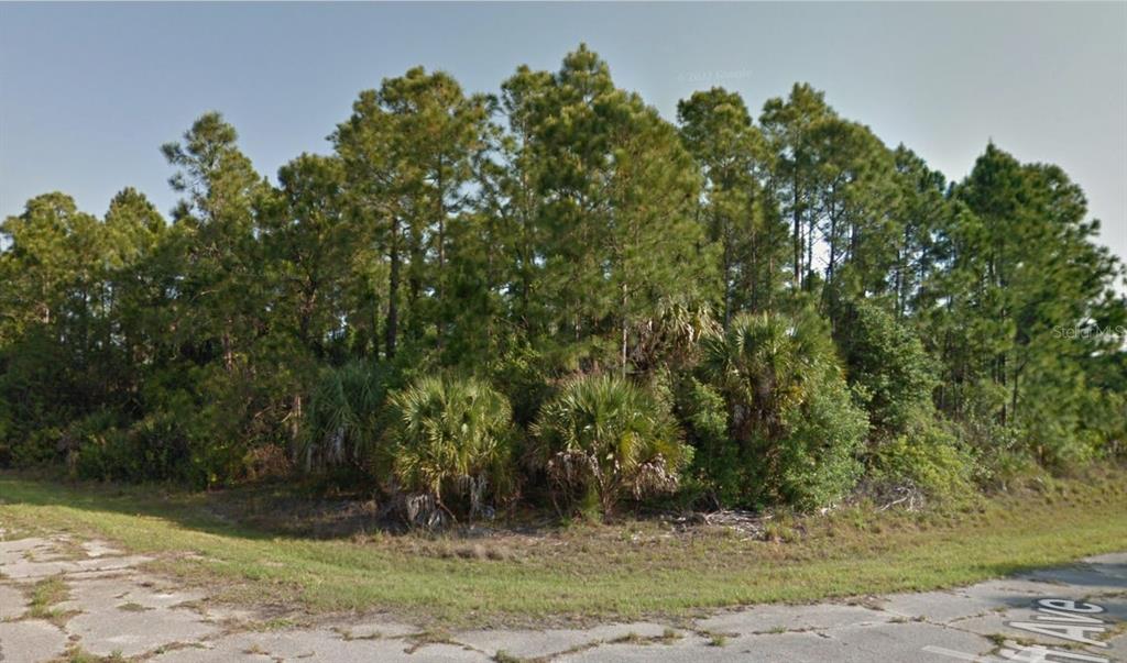 A vacant, wooded corner lot features pine trees and palmettos along a paved street — Lot 18 BRIARCLIFF AVENUE, NORTH PORT, FL