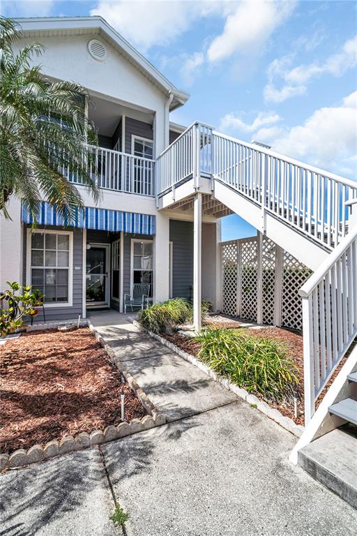 A two-story building features a white exterior, blue striped awnings, and an outdoor staircase — 11531 SHIPWATCH DRIVE UNIT 1037, LARGO, FL