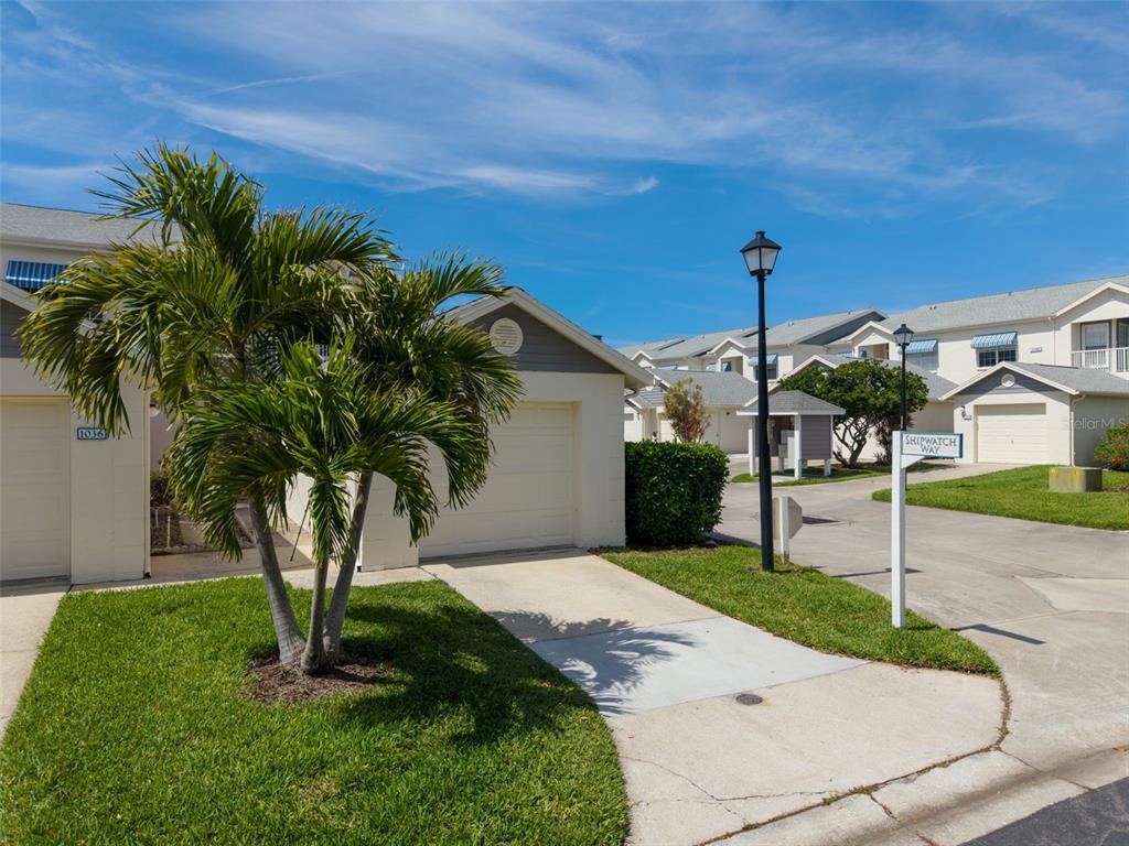 A palm tree stands in front of a residential building with a concrete driveway — 11531 SHIPWATCH DRIVE UNIT 1037, LARGO, FL