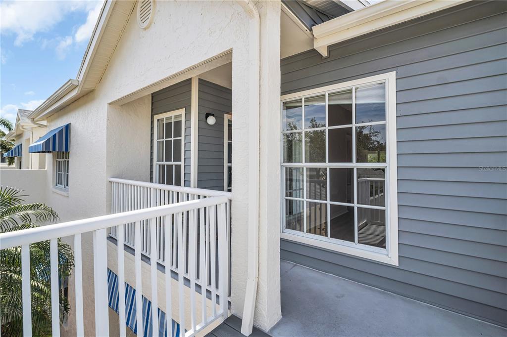 A balcony with white railings, gray siding, and a large window on a residential building — 11531 SHIPWATCH DRIVE UNIT 1037, LARGO, FL