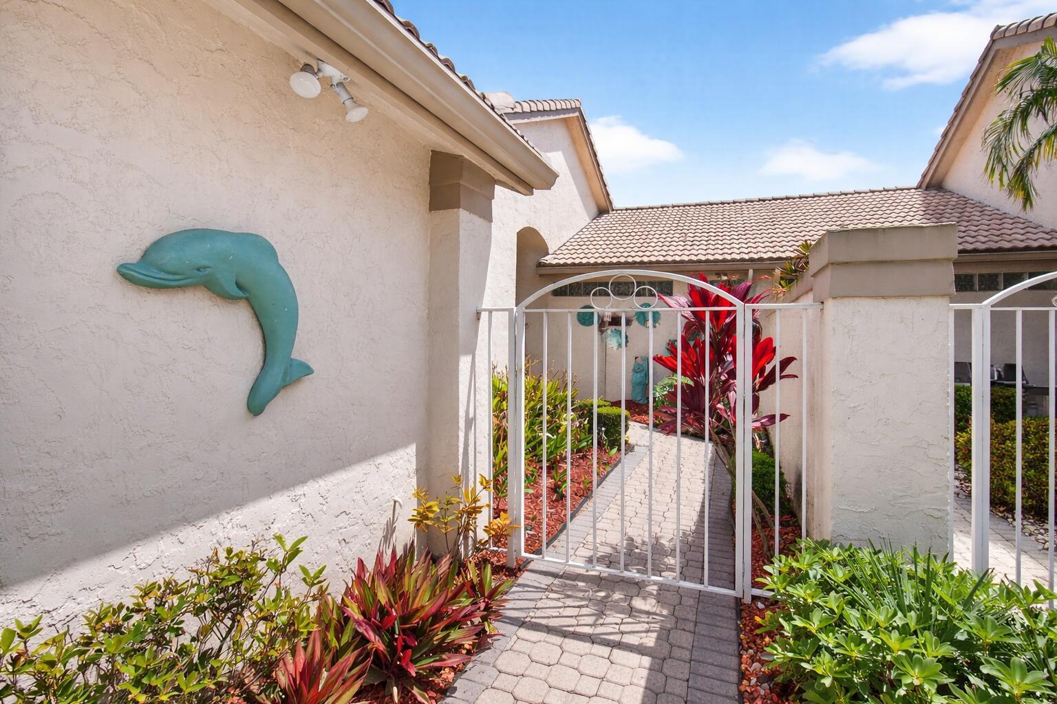 A paved walkway leads through a white metal gate to the entrance of a home — 8864 Shoal Creek Lane, Boynton Beach FL 33472, BOYNTON BEACH, FL