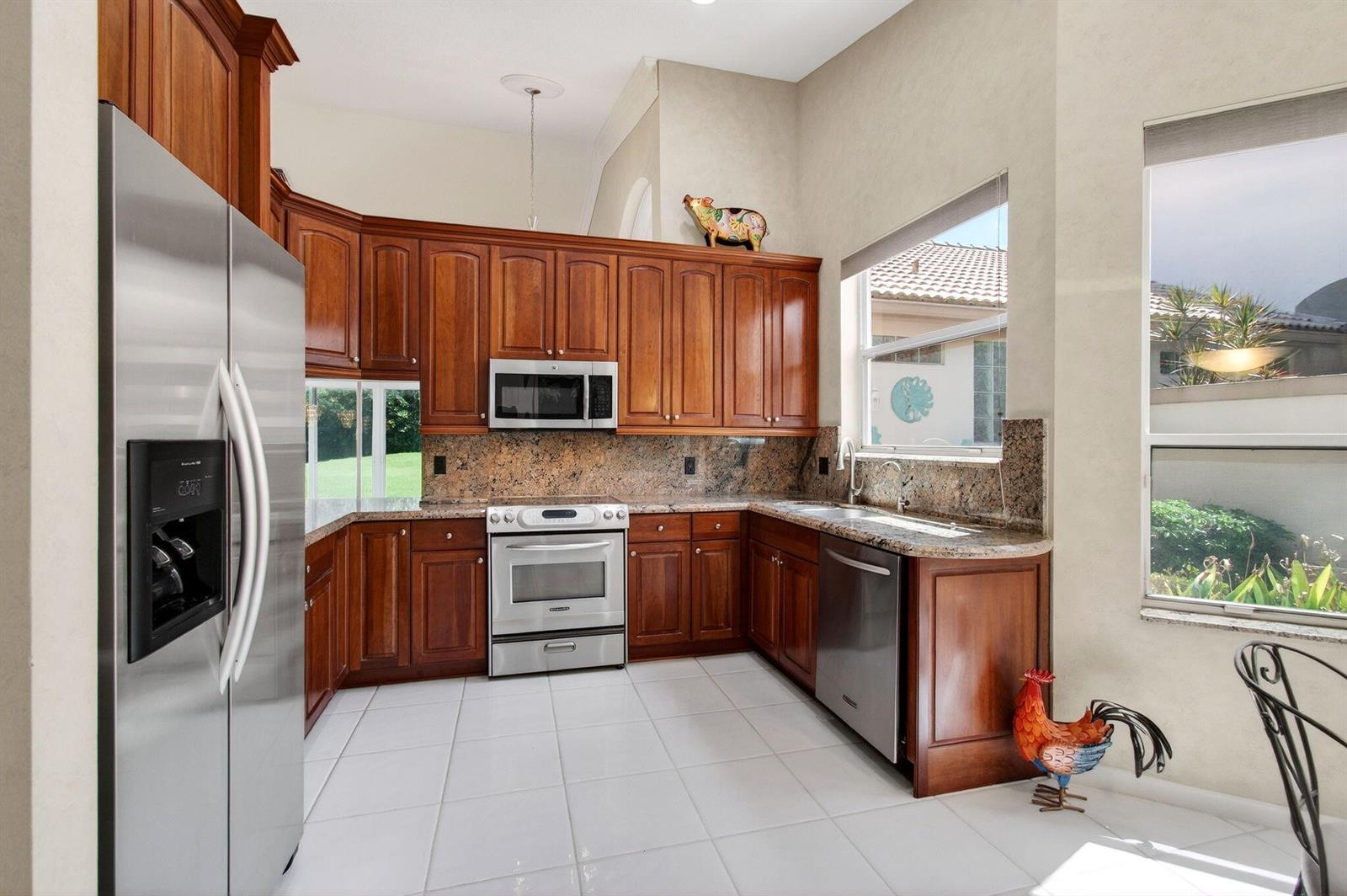 A kitchen with cherry wood cabinets, granite countertops, stainless steel appliances, and white tile floors — 8864 Shoal Creek Lane, Boynton Beach FL 33472, BOYNTON BEACH, FL