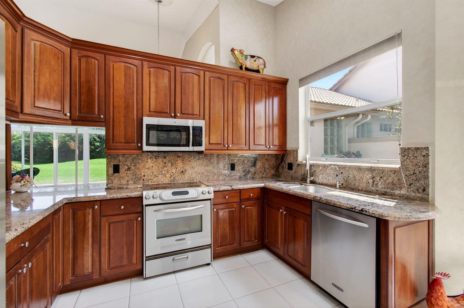 A kitchen with wood cabinets, granite countertops, stainless steel appliances, and a window view — 8864 Shoal Creek Lane, Boynton Beach FL 33472, BOYNTON BEACH, FL
