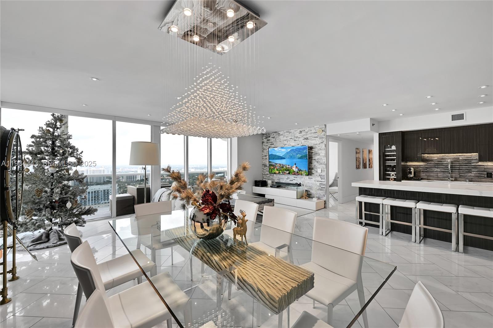 A modern dining area with a glass table, crystal chandelier, and an open kitchen — 1850 S Ocean Dr, Hallandale Beach FL 33009, HALLANDALE BEACH, FL