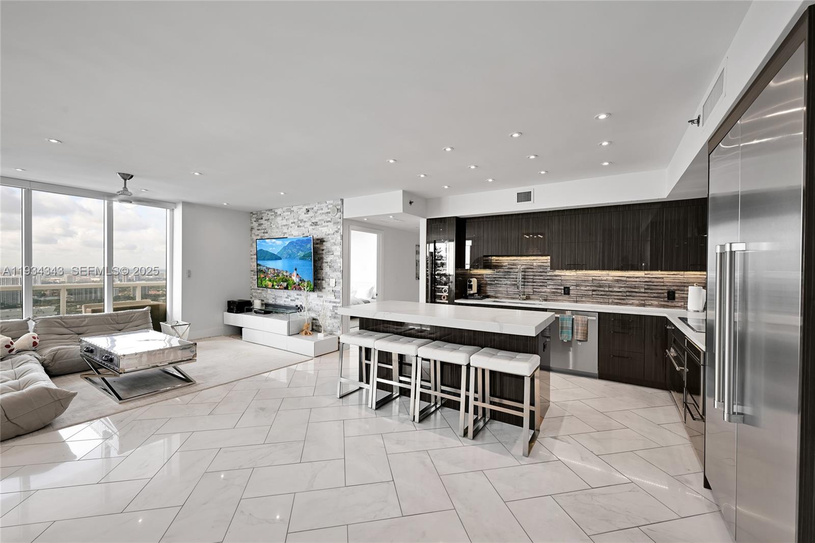 A modern open-concept kitchen and living area features white marble floors and dark cabinetry — 1850 S Ocean Dr, Hallandale Beach FL 33009, HALLANDALE BEACH, FL