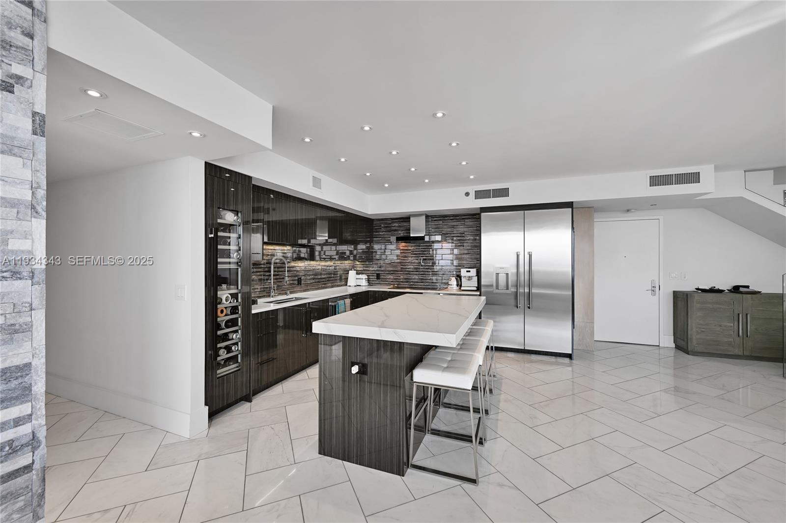 A modern kitchen features dark wood cabinetry, a marble-topped island, and stainless steel appliances — 1850 S Ocean Dr, Hallandale Beach FL 33009, HALLANDALE BEACH, FL