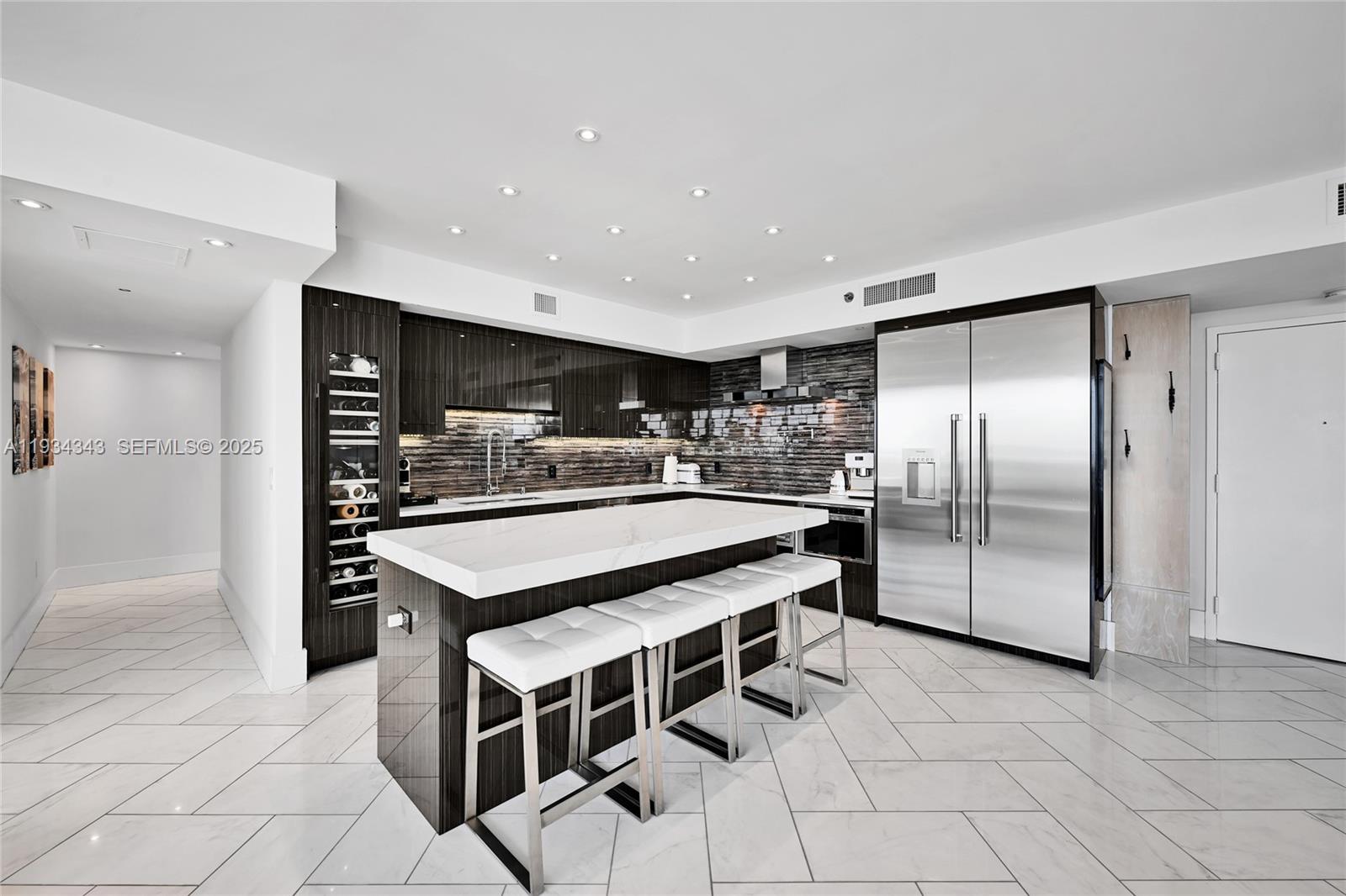 A modern kitchen features dark wood cabinetry, a white marble island, and stainless steel appliances — 1850 S Ocean Dr, Hallandale Beach FL 33009, HALLANDALE BEACH, FL