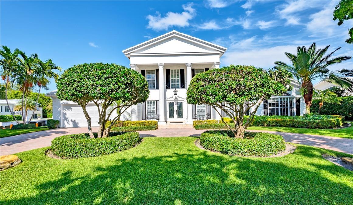 A two-story white house with a columned portico stands behind two manicured, rounded trees — 2 Compass Lane, Fort Lauderdale FL 33308, FORT LAUDERDALE, FL