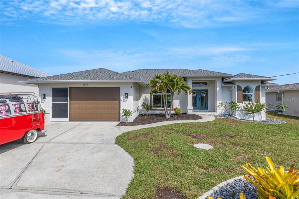 A single-story house with a brown garage door, blue front doors, and a red van parked — 5133 LATHAM TERRACE, PORT CHARLOTTE, FL