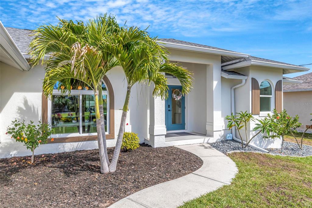The exterior of a single-story house features a blue front door and a palm tree — 5133 LATHAM TERRACE, PORT CHARLOTTE, FL