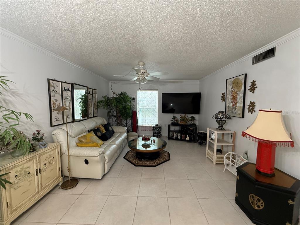 A living room features white tile floors, a white leather sofa, and Asian-inspired decor — 125 PICARDY VILLA CIRCLE UNIT 101, BRANDON, FL
