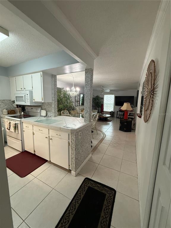 A kitchen with white cabinets and a tiled peninsula opens into a living area — 125 PICARDY VILLA CIRCLE UNIT 101, BRANDON, FL
