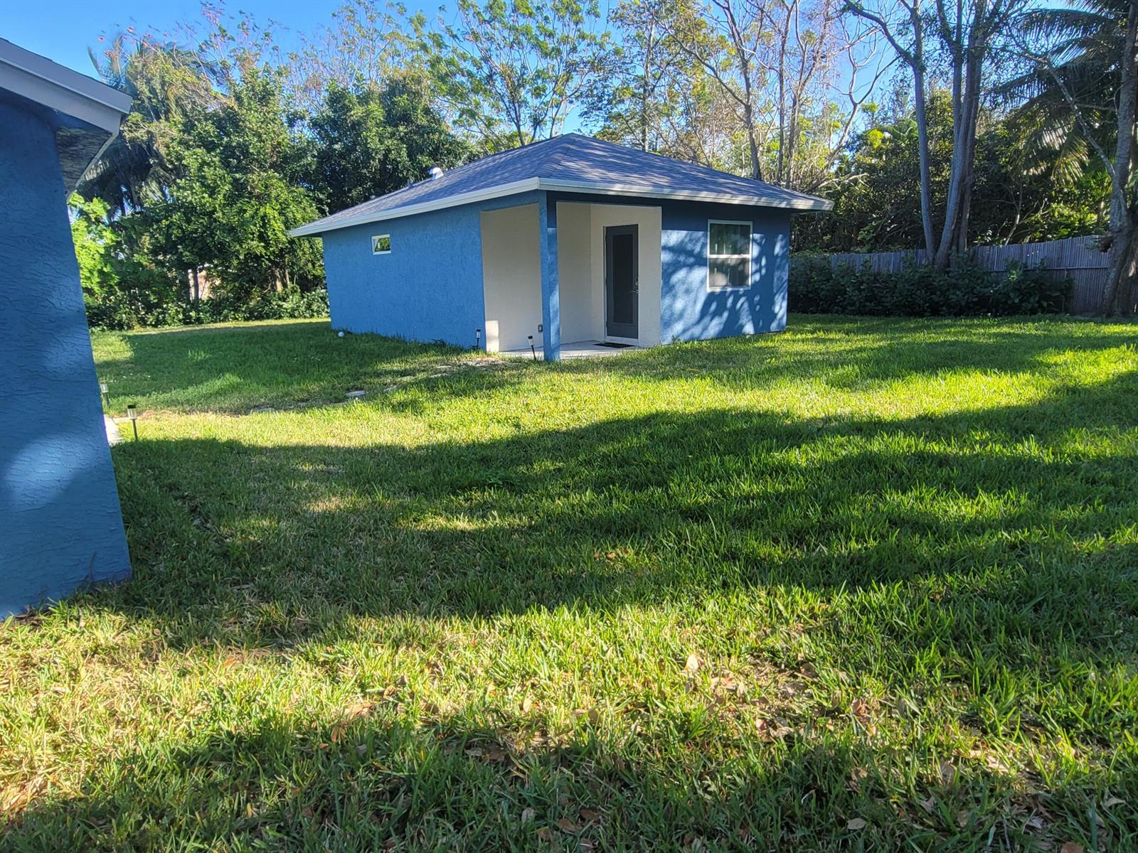 A blue detached building with a small covered porch sits in a grassy backyard — 106 E Chandler Road, Cloud Lake FL 33406, CLOUD LAKE, FL